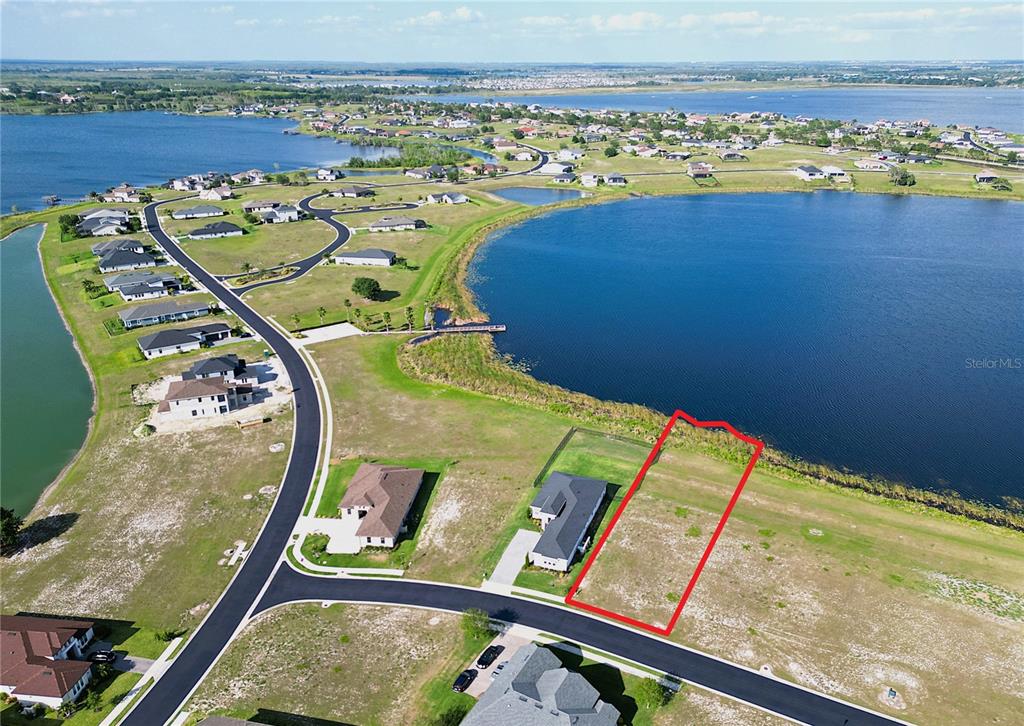 An aerial view shows a vacant residential lot outlined in red next to a lake — 279 SPINNAKER COURT, AUBURNDALE, FL