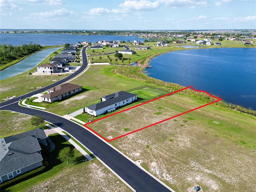 An aerial view shows a vacant residential lot outlined in red next to a lake — 279 SPINNAKER COURT, AUBURNDALE, FL