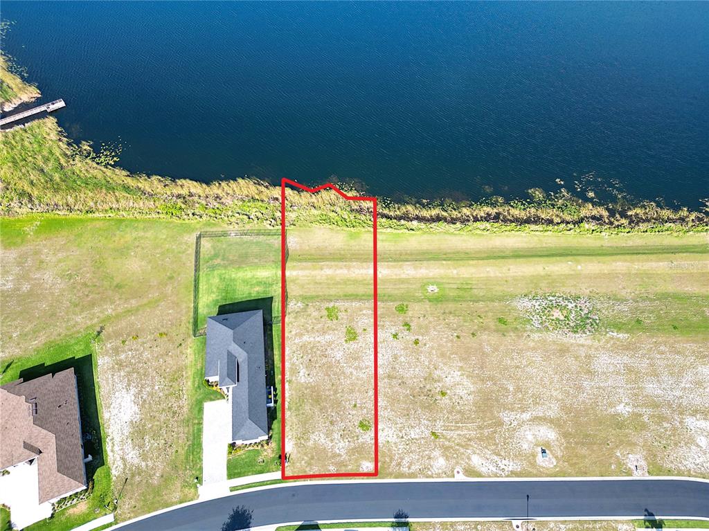 An aerial view shows a vacant residential lot outlined in red bordering a lake — 279 SPINNAKER COURT, AUBURNDALE, FL