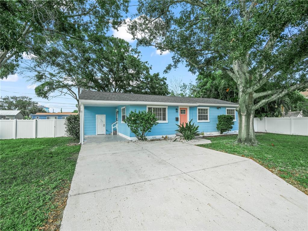 A light blue single-story house with a concrete driveway and a coral-colored front door — 125 80TH AVENUE N, ST PETERSBURG, FL