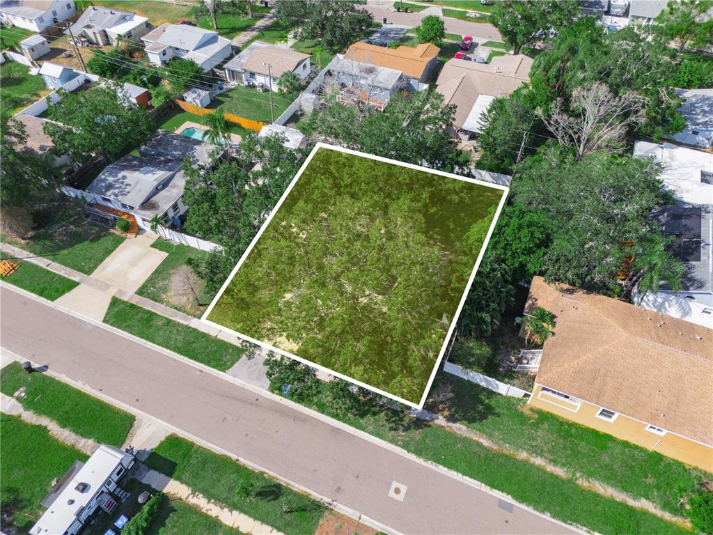 An aerial view shows a vacant, tree-covered residential lot situated between two existing houses — 125 80TH AVENUE N, ST PETERSBURG, FL
