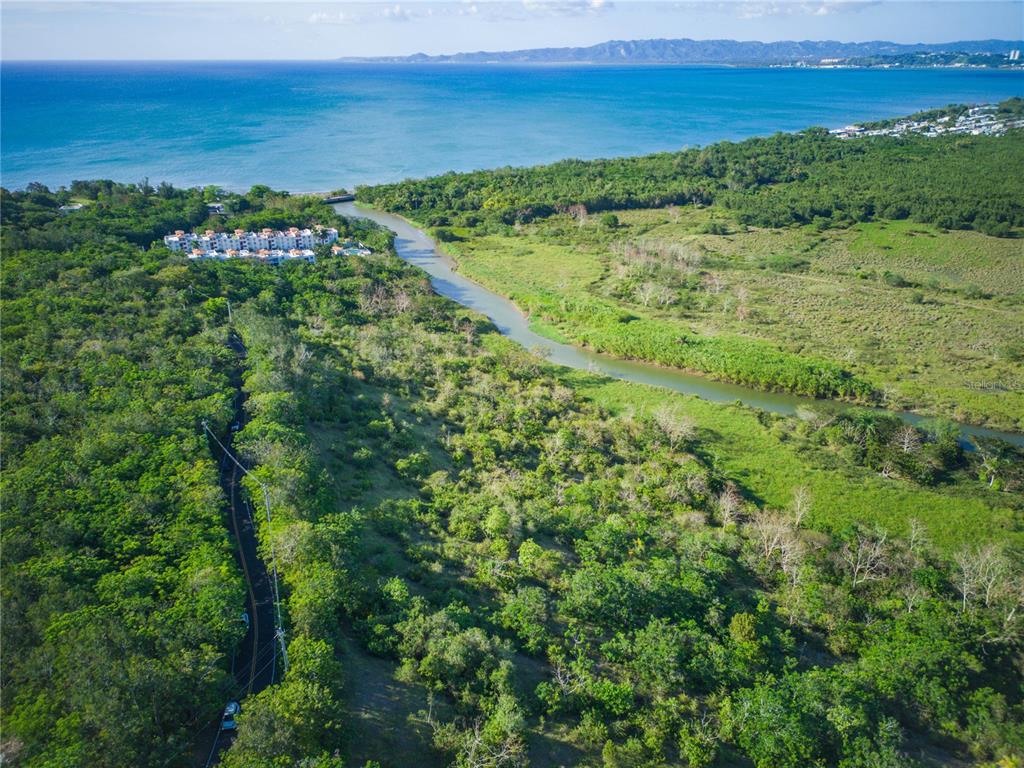 An aerial view shows a winding river flowing through a lush landscape toward the ocean — 102 KM 8.2, GUANAJIBO WARD ROAD UNIT C-6, CABO ROJO, PR