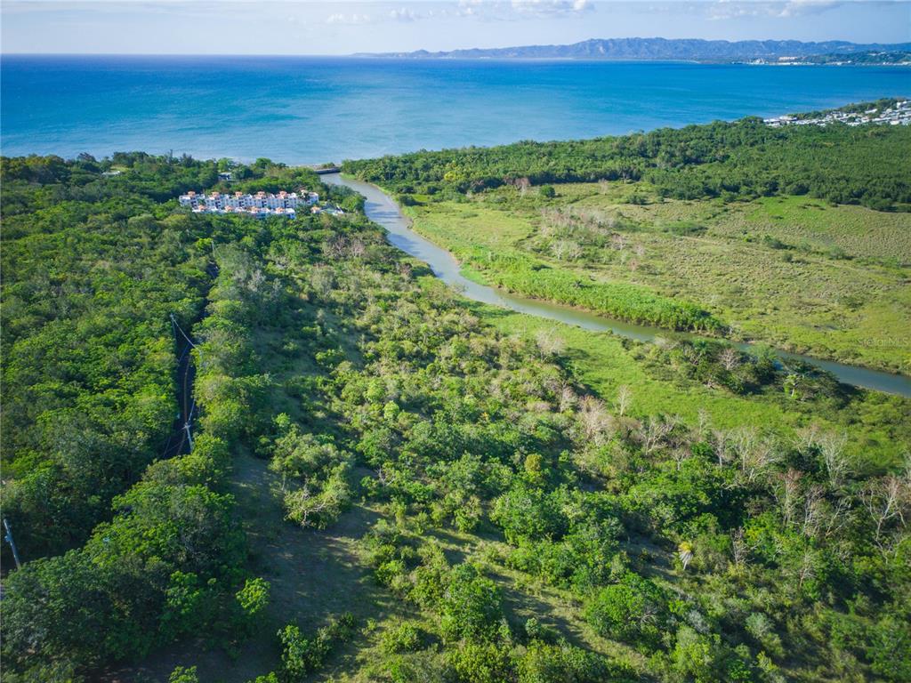 An aerial view shows a winding river flowing through a lush landscape toward the ocean — 102 KM 8.2, GUANAJIBO WARD ROAD UNIT C-6, CABO ROJO, PR