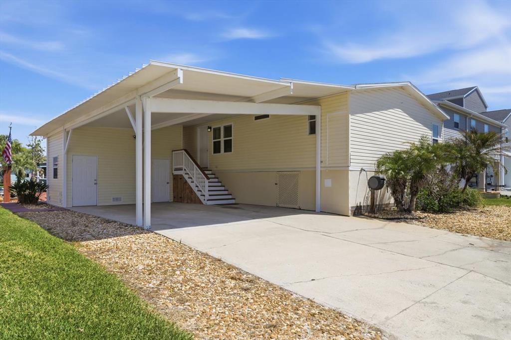 A light yellow manufactured home features a large covered carport and concrete driveway — 11673 W CLEARWATER COURT, HOMOSASSA, FL