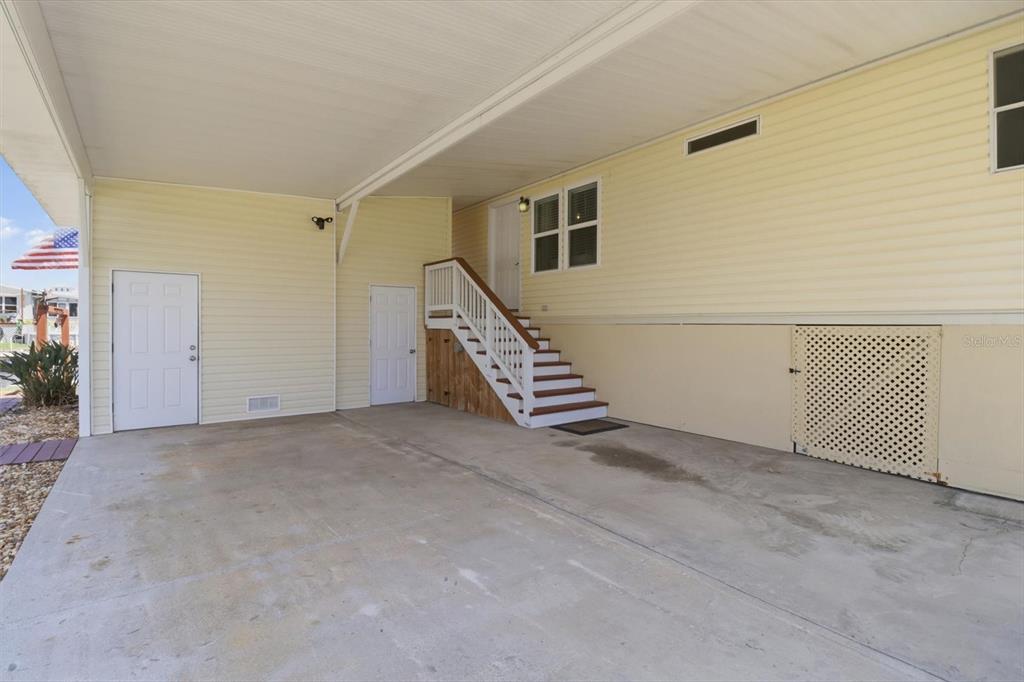 A concrete carport area features a staircase leading to an elevated home entrance — 11673 W CLEARWATER COURT, HOMOSASSA, FL