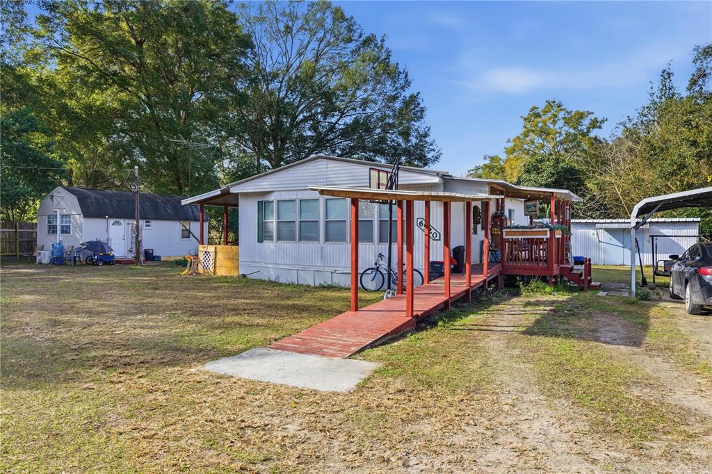 A single-story mobile home features a red wooden ramp leading to a covered front porch — 6520 NE 23RD AVENUE, OCALA, FL
