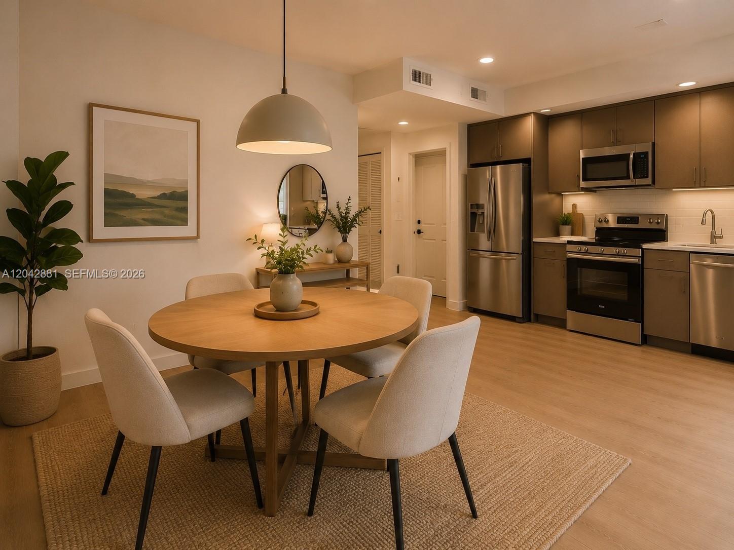 A dining area with a round wooden table sits adjacent to a modern kitchen — 8106 NE 1st Ave # 6, Miami FL 33138, MIAMI, FL