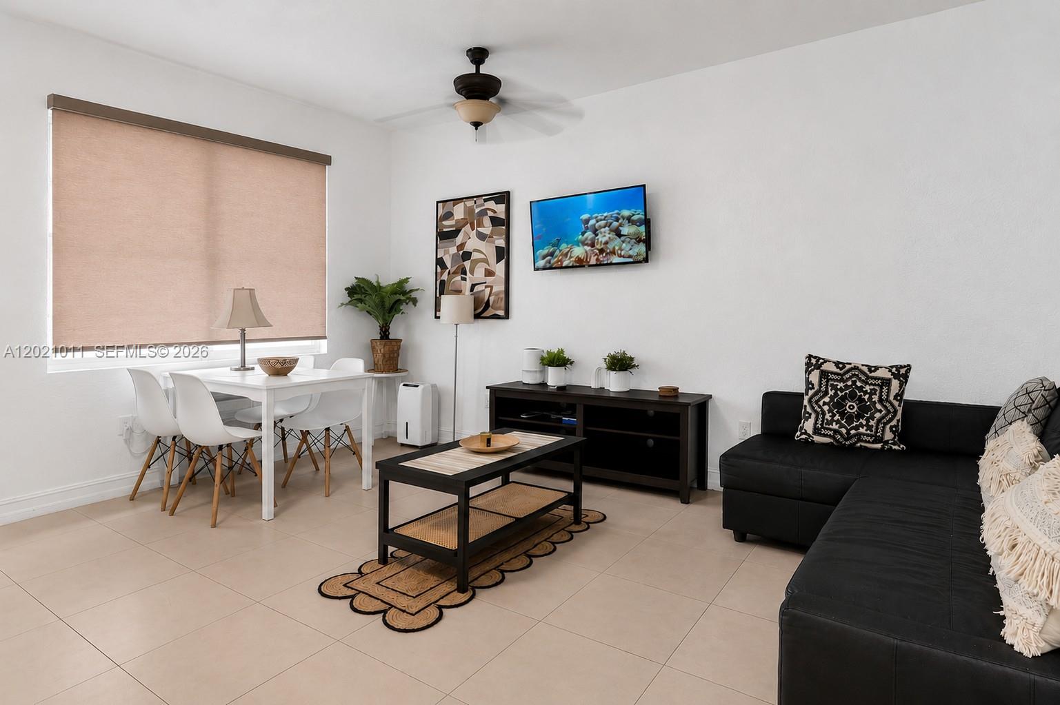 A living and dining area features white walls, tile floors, a black sofa, and furniture — 500 14th St # 101, Miami Beach FL 33139, MIAMI BEACH, FL