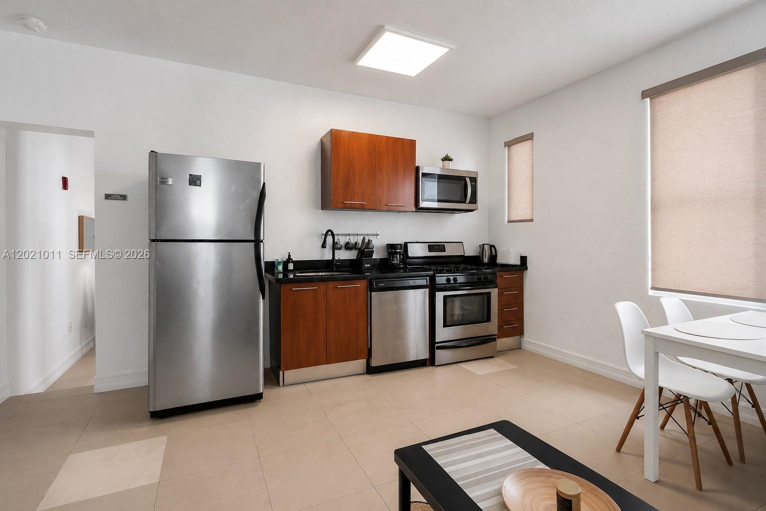 This kitchen features stainless steel appliances, wood cabinets, and light tile flooring — 500 14th St # 101, Miami Beach FL 33139, MIAMI BEACH, FL