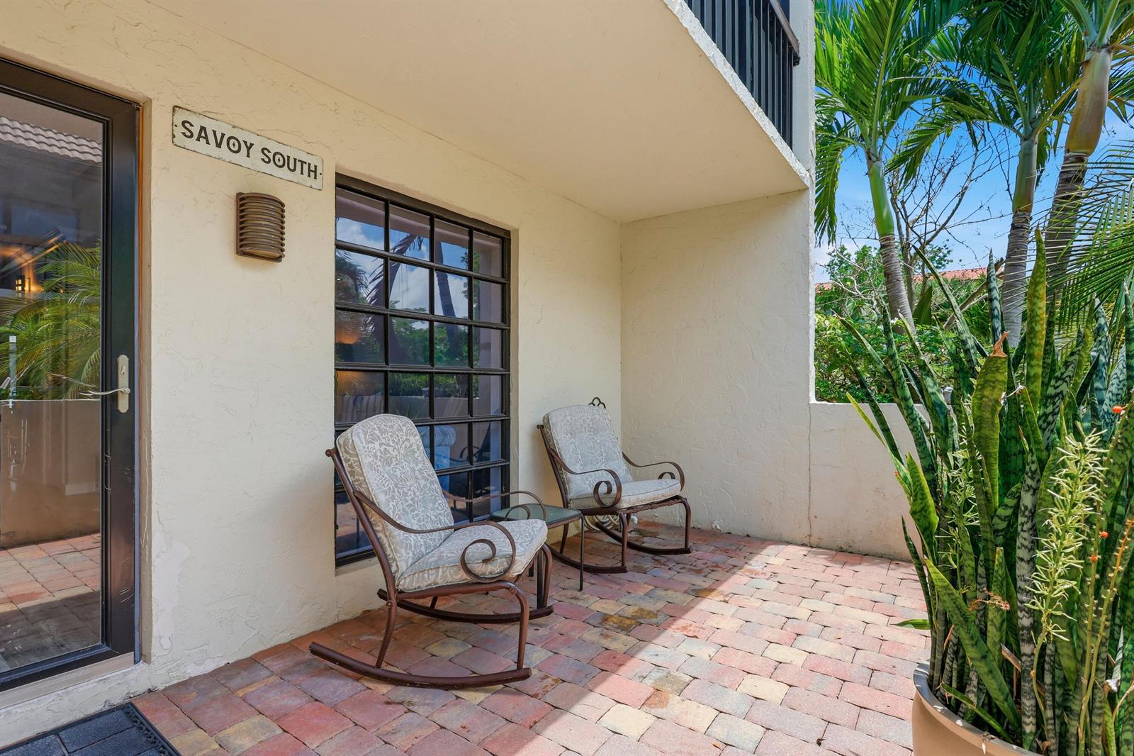 A patio with brick pavers, two rocking chairs, and a sign reading Savoy South — 721 SE 1st Way # C11, Deerfield Beach FL 33441, DEERFIELD BEACH, FL