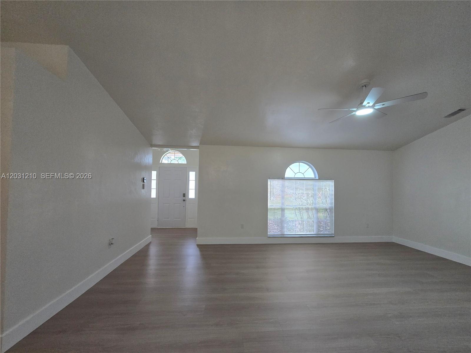 An empty living room features light wood-look flooring, white walls, and a ceiling fan — 8309 SW 61st Place # 1, Gainesville FL 32608, GAINESVILLE, FL