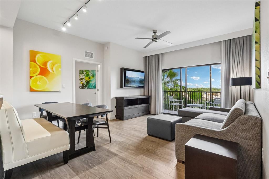 A living and dining area features wood flooring, a sectional sofa, and a balcony view — 14501 GROVE RESORT AVENUE UNIT 2342, WINTER GARDEN, FL