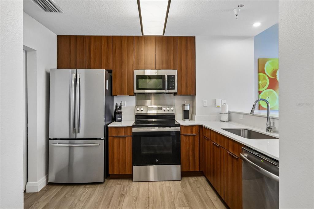 A kitchen features stainless steel appliances, wood-toned cabinetry, and white countertops — 14501 GROVE RESORT AVENUE UNIT 2342, WINTER GARDEN, FL