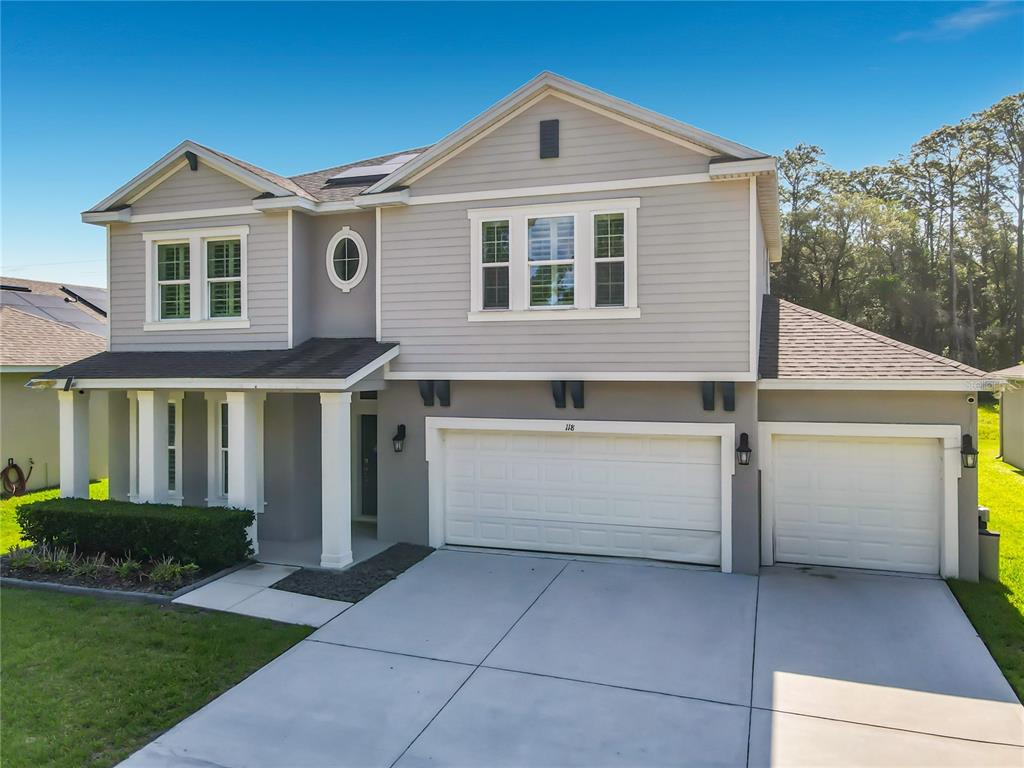 A two-story suburban house features gray siding, a white garage, and a concrete driveway — 118 VICTORIA OAKS BOULEVARD, DELAND, FL