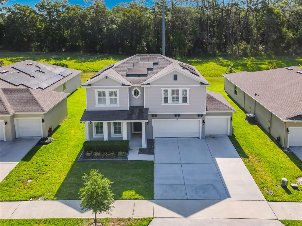 An aerial view of a two-story suburban house with a three-car garage and solar panels — 118 VICTORIA OAKS BOULEVARD, DELAND, FL