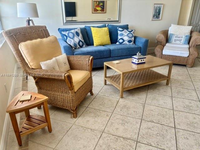 A living room features a wicker armchair, a blue sofa, and a wooden coffee table — 100 Lincoln Rd # 1434, Miami Beach FL 33139, MIAMI BEACH, FL