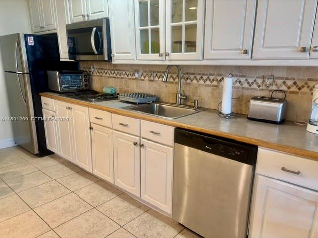 A kitchen features white cabinets, stainless steel appliances, a tiled backsplash, and light-colored countertops — 100 Lincoln Rd # 1434, Miami Beach FL 33139, MIAMI BEACH, FL