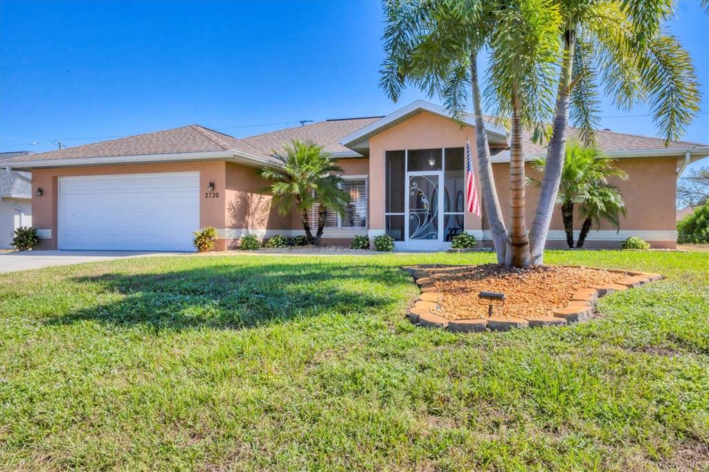 A single-story house with a two-car garage, a screened entryway, and palm trees — 2720 S BISCAYNE DRIVE, NORTH PORT, FL