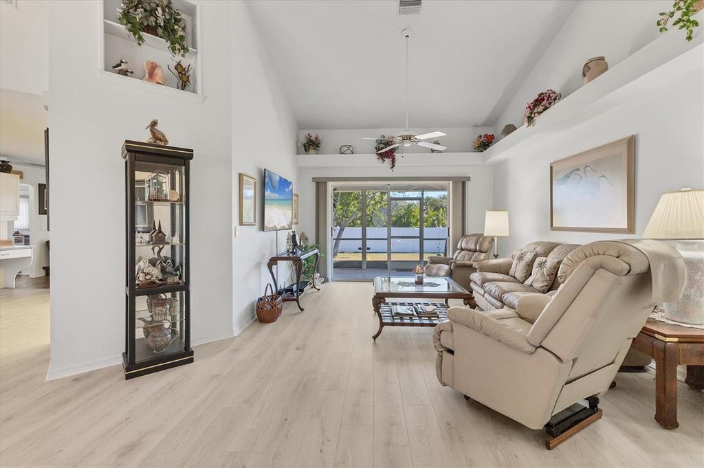 A living room features light wood-look flooring, a vaulted ceiling, and a sliding glass door — 2720 S BISCAYNE DRIVE, NORTH PORT, FL