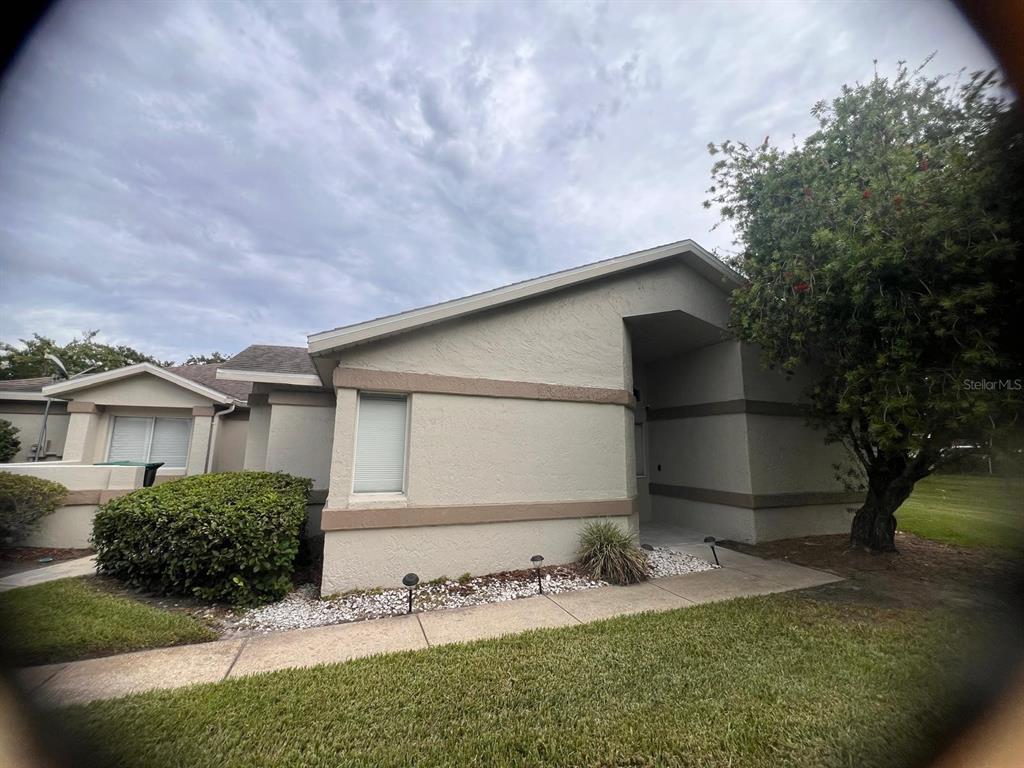 A single-story stucco house with a recessed entryway, a small lawn, and a large tree — 535 AZINGER CIRCLE UNIT 16, ORLANDO, FL