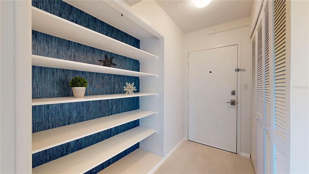 An entryway features built-in white shelves against a blue textured wall and louvered closet doors — 2401 BAYSHORE BLVD UNIT 502, TAMPA, FL