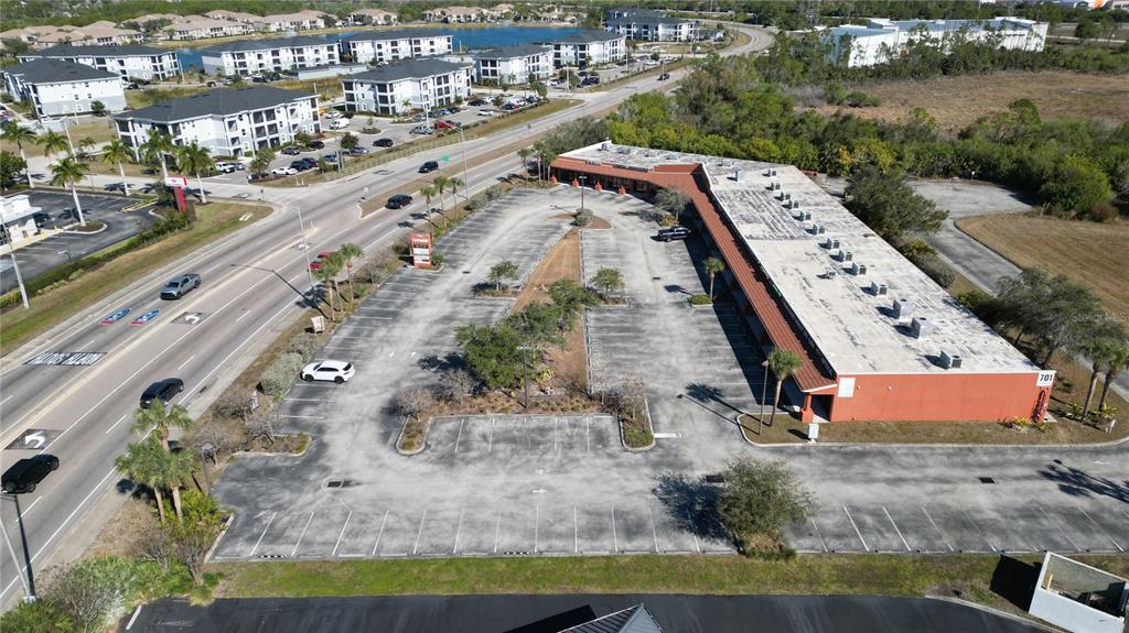 An aerial view shows a commercial building with a large parking lot and surrounding roads — 701 J C CENTER COURT UNIT 8, PORT CHARLOTTE, FL