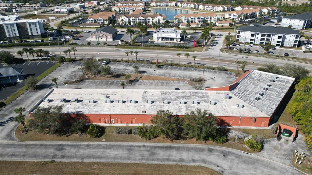 An aerial view of a long, red-walled commercial building with a large parking lot — 701 J C CENTER COURT UNIT 8, PORT CHARLOTTE, FL