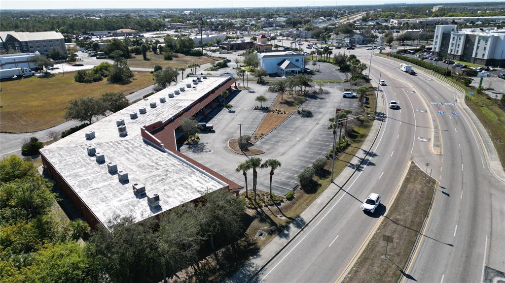 An aerial view shows a commercial building with a large parking lot beside a highway — 701 J C CENTER COURT UNIT 8, PORT CHARLOTTE, FL