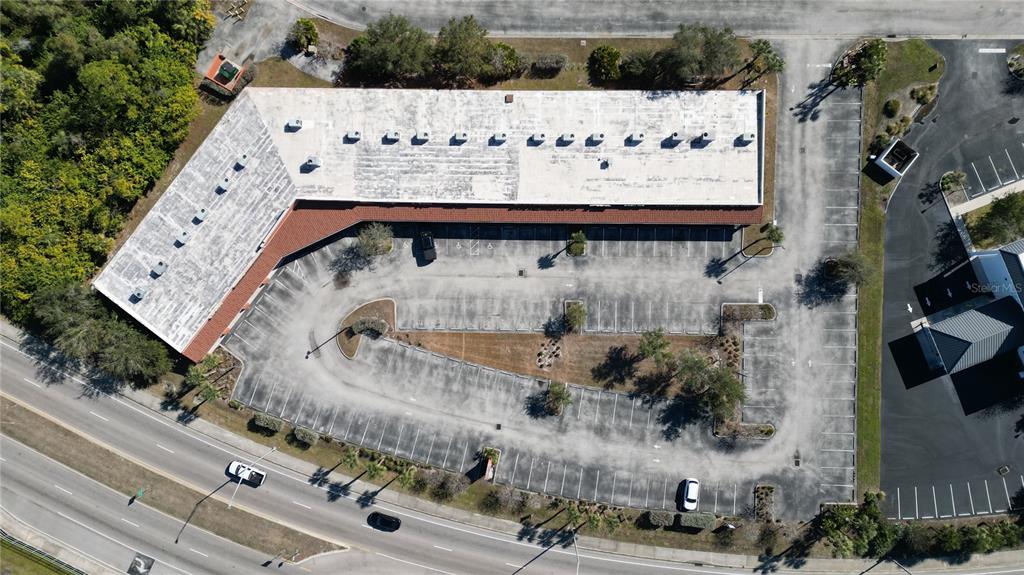 An aerial view shows a commercial building with a large parking lot and surrounding trees — 701 J C CENTER COURT UNIT 8, PORT CHARLOTTE, FL