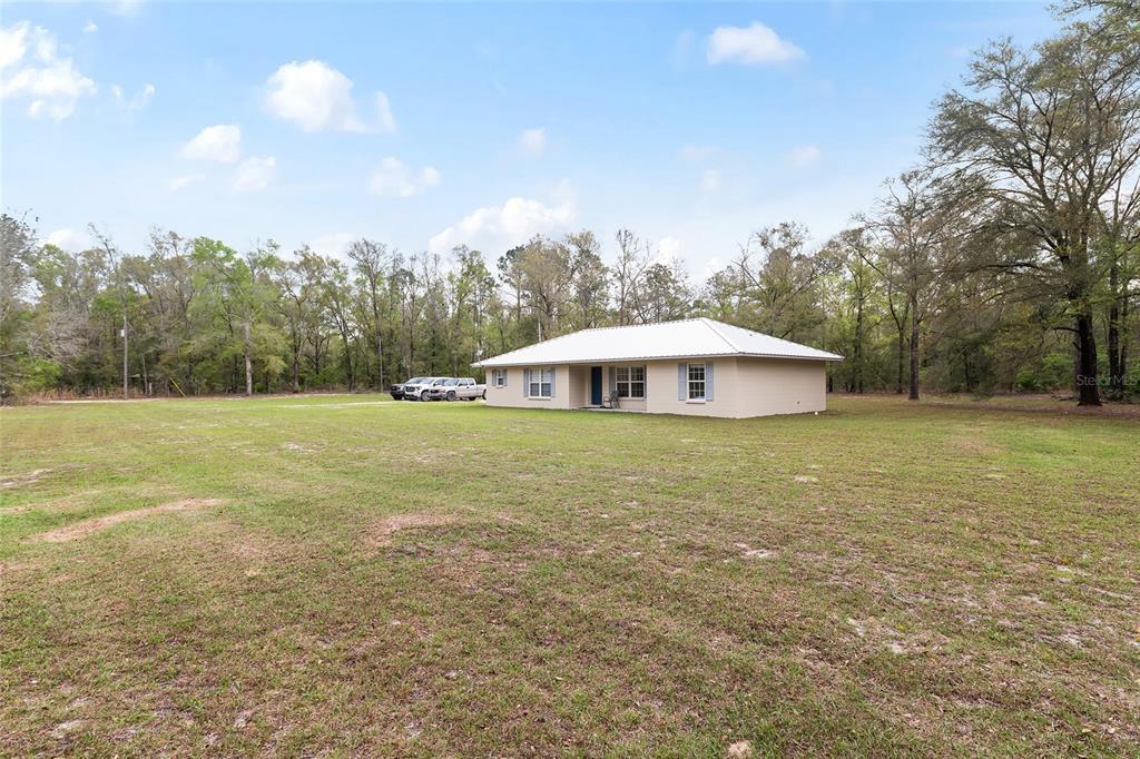 A single-story house with a metal roof sits on a large, grassy lot — 2610 NE 80TH AVENUE, HIGH SPRINGS, FL