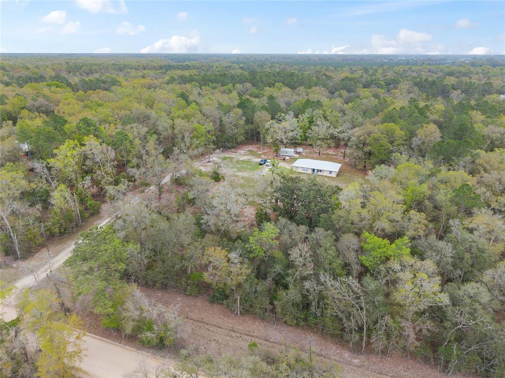 An aerial view shows a single-story house situated on a large, wooded rural lot — 2610 NE 80TH AVENUE, HIGH SPRINGS, FL