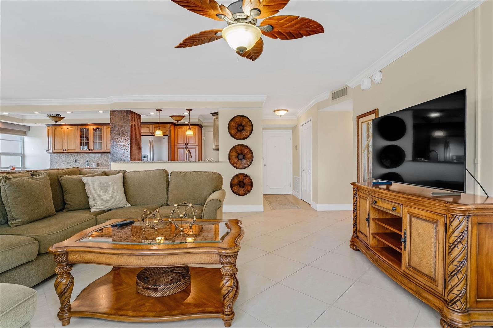 A living room features a green sectional sofa, a wooden coffee table, and a television — 133 N Pompano Beach Boulevard # 501, Pompano Beach FL 33062, POMPANO BEACH, FL