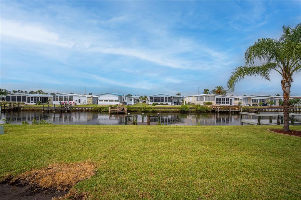 A grassy lawn overlooks a canal lined with mobile homes and private boat docks — 646 BLACKBURN BOULEVARD, NORTH PORT, FL