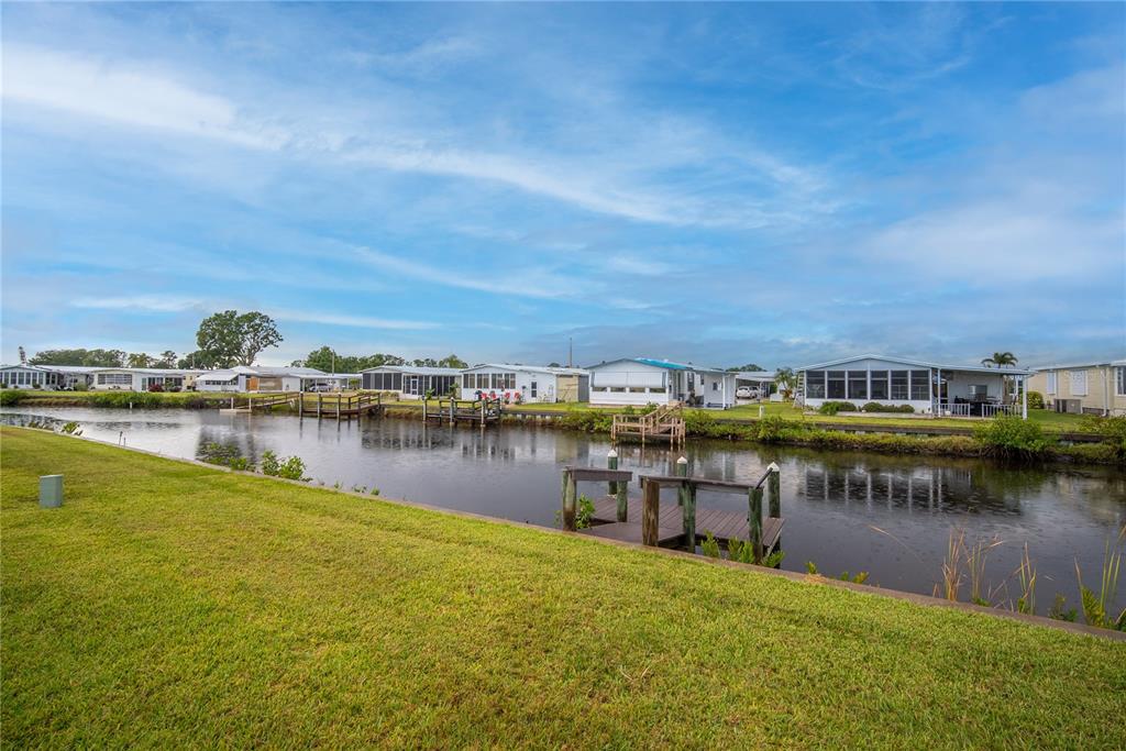 A canal view showing a grassy lawn, wooden docks, and several mobile homes in Florida — 646 BLACKBURN BOULEVARD, NORTH PORT, FL