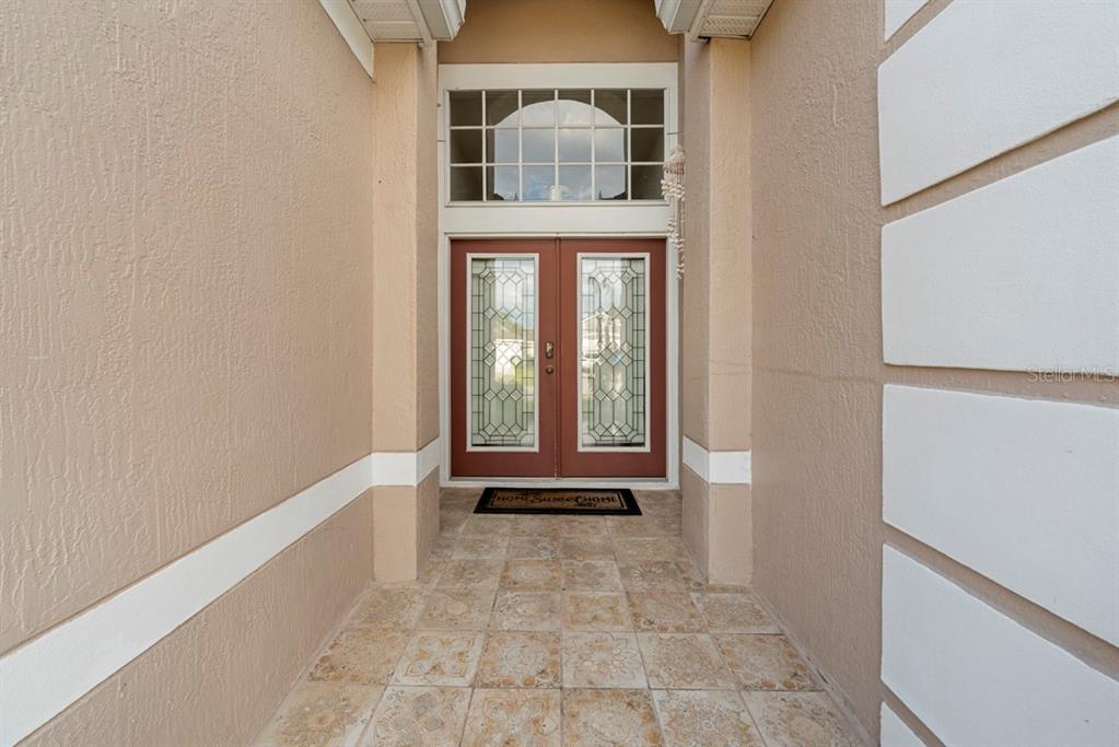 A covered entryway features a tiled floor and double doors with glass inserts and a transom — 3181 STONEHURST CIRCLE, KISSIMMEE, FL