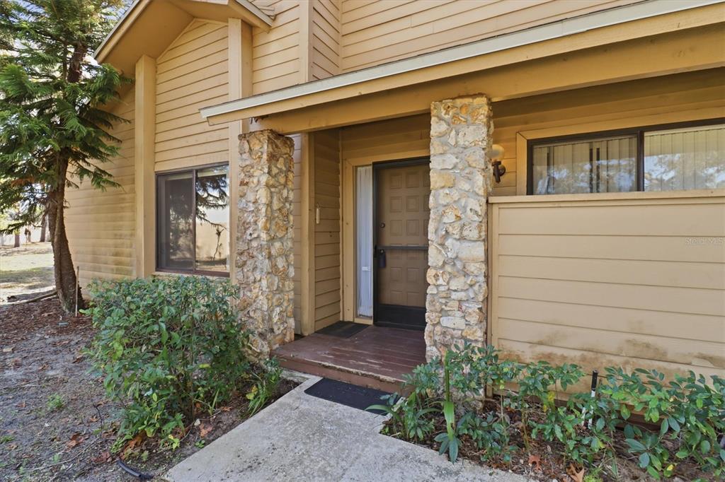 The exterior of a house features horizontal siding, stone pillars, and a covered front entryway — 519 STANTON PLACE, LONGWOOD, FL