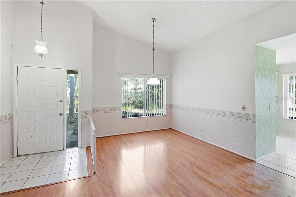An entryway and dining area feature wood-look flooring, white walls, and a vaulted ceiling — 519 STANTON PLACE, LONGWOOD, FL