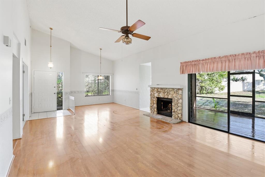A living room features light wood flooring, a stone fireplace, and a vaulted ceiling — 519 STANTON PLACE, LONGWOOD, FL
