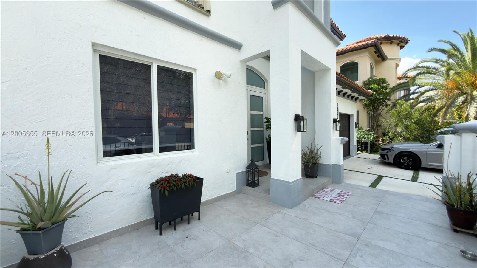 The exterior of a white house features a tiled entryway, a large window, and potted plants — 2180 SW 152nd Pl, Miami FL 33185, MIAMI, FL