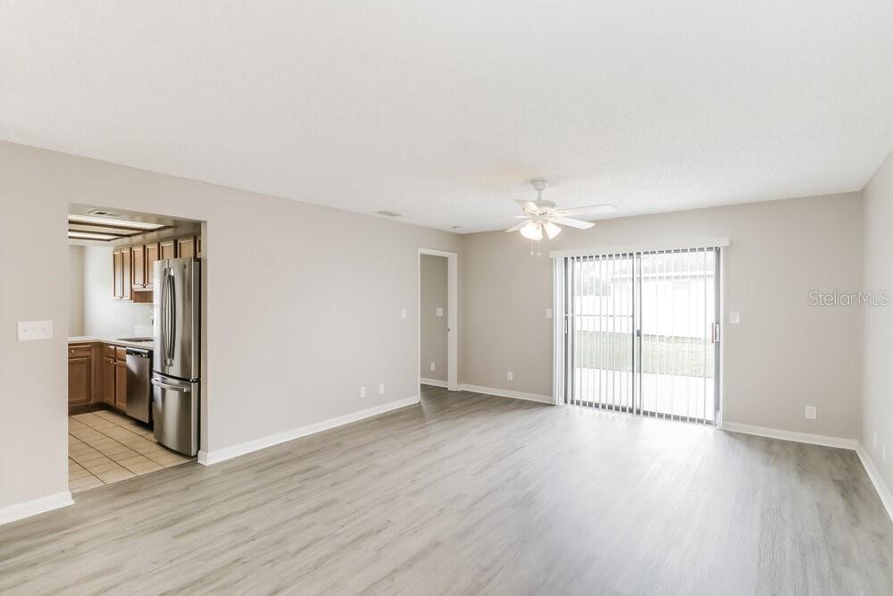 An open living area with light-colored walls, wood-look flooring, and a sliding glass door — 23106 MAYFAIR ROAD, LAND O LAKES, FL
