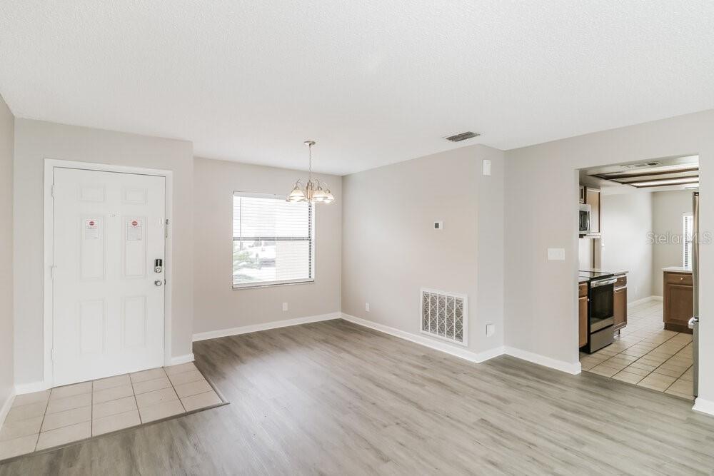 A dining area with wood-look flooring, a white front door, and an adjacent kitchen — 23106 MAYFAIR ROAD, LAND O LAKES, FL