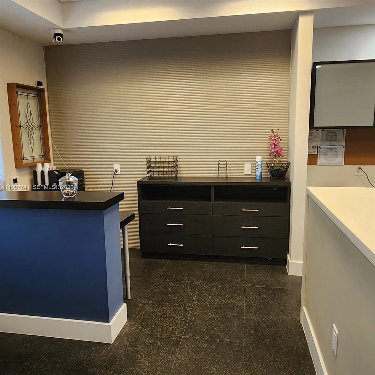 A reception area features a blue counter, dark wood cabinets, and a textured wall — 2441 NW 93 # B, Doral FL 33172, DORAL, FL