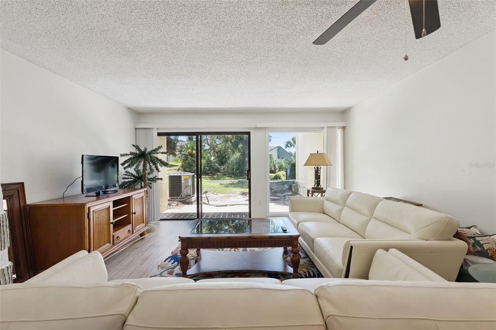 A living room features white leather sofas, a wooden coffee table, and sliding glass doors — 201 CLUB HOUSE BOULEVARD UNIT 201, NEW SMYRNA BEACH, FL