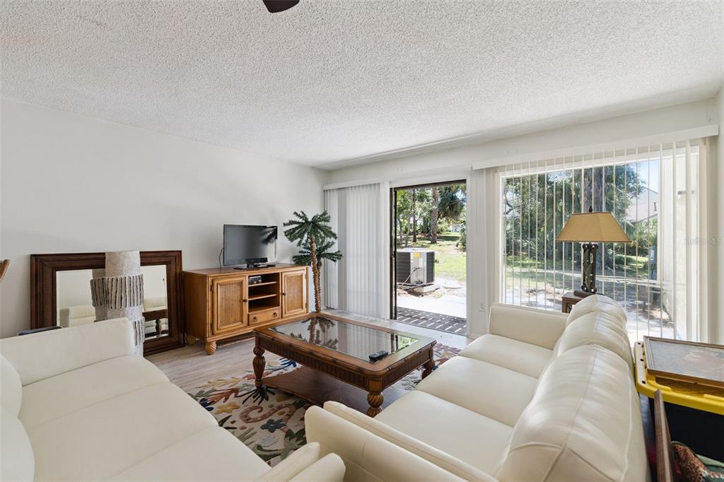A living room features white sofas, a wooden coffee table, and sliding glass doors — 201 CLUB HOUSE BOULEVARD UNIT 201, NEW SMYRNA BEACH, FL
