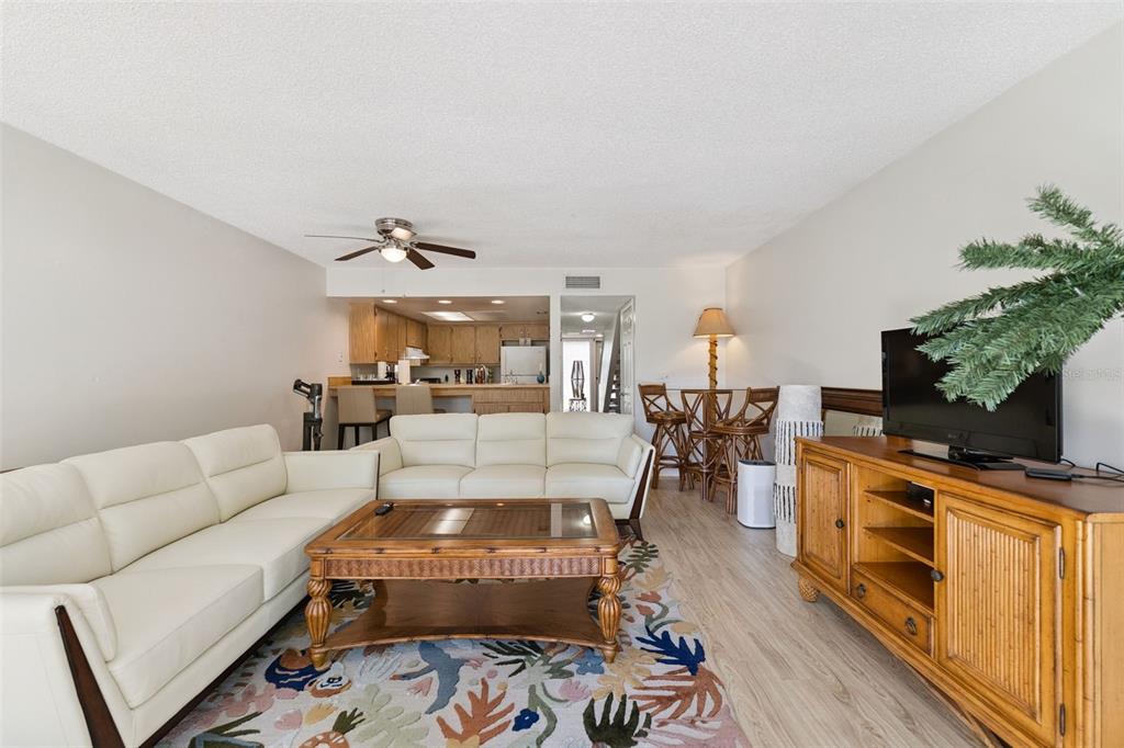 A living room with white sofas, a wooden coffee table, and an adjacent kitchen area — 201 CLUB HOUSE BOULEVARD UNIT 201, NEW SMYRNA BEACH, FL