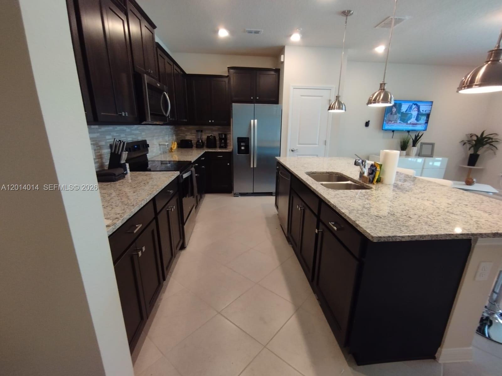 A kitchen features dark wood cabinets, granite countertops, stainless steel appliances, and a central island — 1292 BLUE ISLAND DRIVE # 1292, Clermont FL 34714, CLERMONT, FL