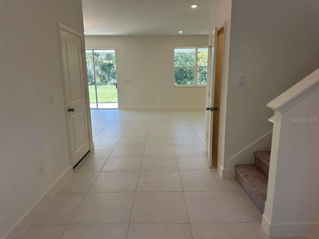 An interior view showing a tiled entryway leading to a living area with sliding doors — 3449 SANCTUARY DRIVE, CLERMONT, FL