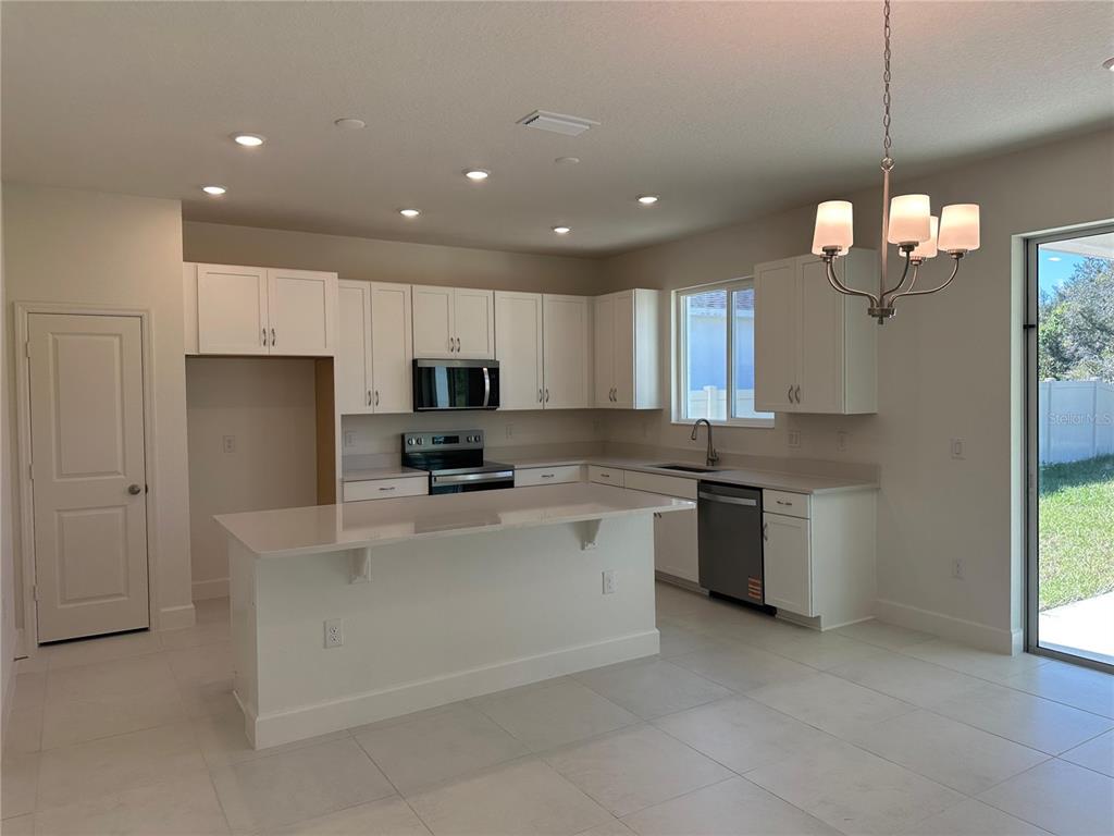 A kitchen with white cabinets, a central island, stainless steel appliances, and tile flooring — 3449 SANCTUARY DRIVE, CLERMONT, FL