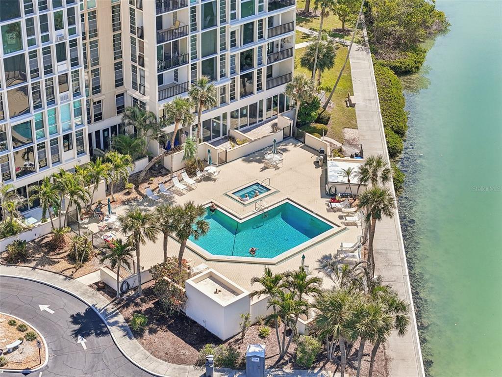 An aerial view shows a swimming pool and hot tub beside a tall residential building — 7400 SUN ISLAND DRIVE S UNIT 712, SOUTH PASADENA, FL
