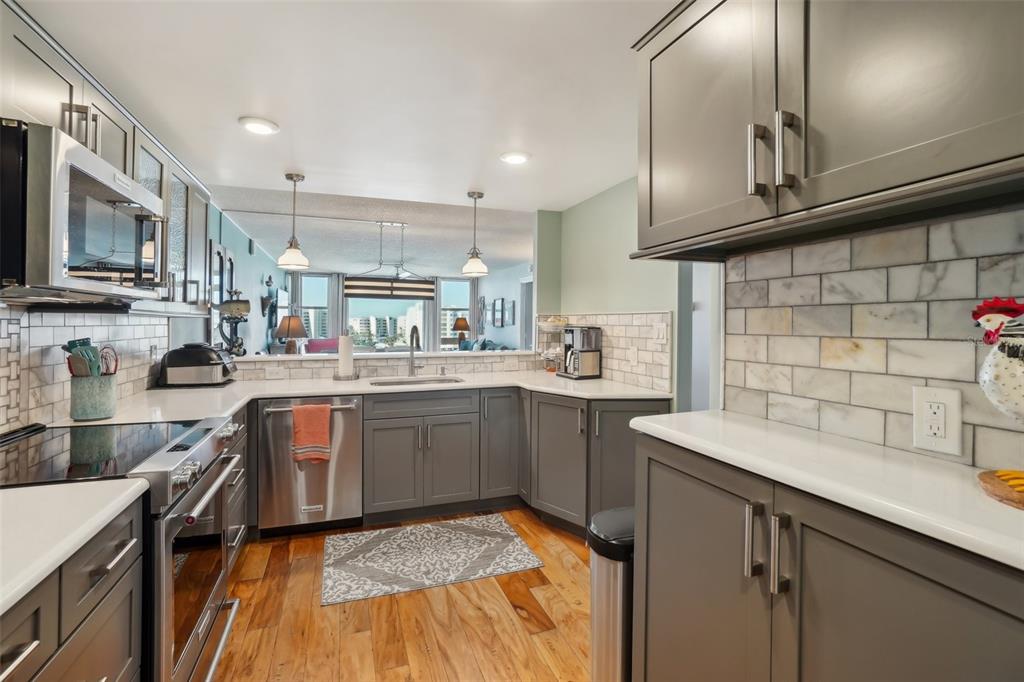 A kitchen with gray cabinets, white countertops, stainless steel appliances, and a subway tile backsplash — 7400 SUN ISLAND DRIVE S UNIT 712, SOUTH PASADENA, FL